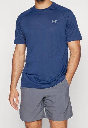 Marineblauw sportshirt met korte mouwen en ronde hals, vergezeld van lichtgrijze logo, gecombineerd met grijze shorts met zijzakken en een elastische tailleband.