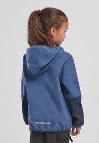 Blauwe jas met capuchon, donkerblauwe mouwen, gestructureerde stof en reflecterende streep nabij de zoom. Achteraanzicht dat ontwerpelementen toont.