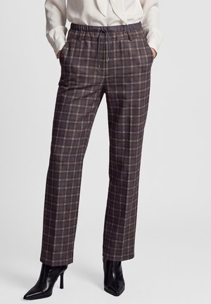 Woman wearing gray and brown plaid straight-leg pants with an elastic waistband and drawstring, paired with black pointed-toe high-heel boots.