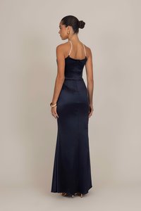 Navy satin iltaväri iltapuku, jossa on napakkasti istuva hame, spaghetti-hihnat ja levenevä helma, jokaominaistaa sileän tekstuurin ja minimalistisen muotoilun.