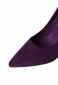 Tacco a punta in suede viola con una fodera interna liscia. La scarpa presenta una silhouette snella e una texture sottile.