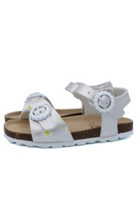 Sandales blanches avec motifs floraux, semelle en liège, brides réglables et boutons décoratifs. Semelle en caoutchouc texturée pour une meilleure adhérence.