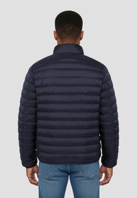 Doudoune matelassée bleu marine avec col montant, motif matelassé horizontal et poignets élastiques. Conçue avec une coupe décontractée et un matériau léger.