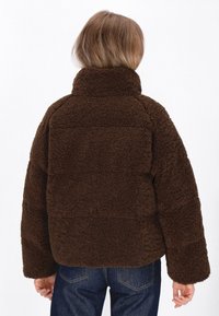 Braune, flauschige Fleecejacke mit hohem Kragen, überschnittenen Schultern und kastiger Passform. Strukturiertes Material mit gesticktem Muster.