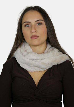 Femme aux longs cheveux noirs portant un haut noir et une épaisse écharpe en fausse fourrure gris clair enroulée autour de son cou.