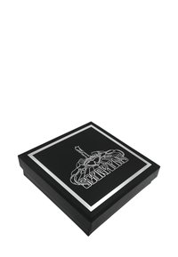 Caja cuadrada negra con un borde plateado y un diseño de escorpión en blanco en la parte superior; tiene una textura suave y una apariencia moderna y elegante.