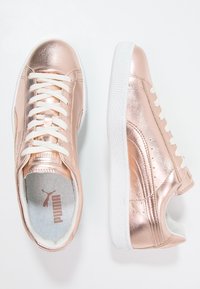 Rosa guldmetalliska sneakers med vita sulor, med en slät yta, rund tå och traditionell snörning.