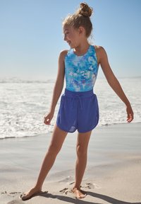 Plavkový set pozostávajúci z modrého tielka s abstraktným vzorom a modrých sieťovaných šortiek, s priliehavým strihom a sťahovacou šnúrkou v páse.