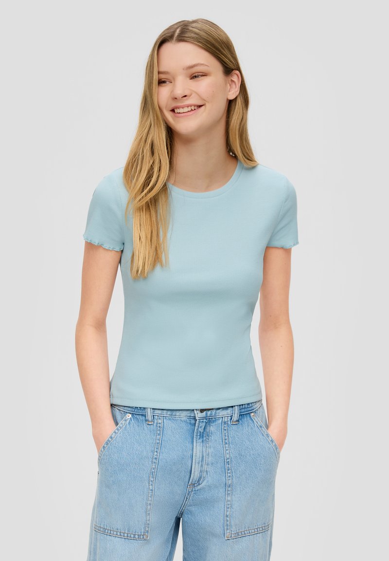 Lichtblauwe geribbelde T-shirt met korte mouwen, met een ronde halslijn en gekartelde randen, gecombineerd met lichtgewassen denim broek.