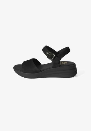 Sandale noire à bout ouvert avec bride de cheville réglable, fermeture à boucle, semelle rembourrée et petit talon compensé sur fond blanc.