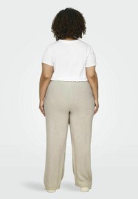 Witte T-shirt met korte mouwen gecombineerd met lichtbeige wijde broek, voorzien van een geplooide elastische tailleband en een gladde, gestructureerde stof.