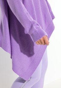 Maglione lavorato a maglia lilla con vestibilità ampia, polsini a coste e orlo triangolare. Il tessuto appare morbido con una texture liscia.