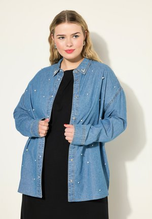 Blauwe denim blouse met parelaccenten, lange mouwen en een kraag, over een zwarte jurk.