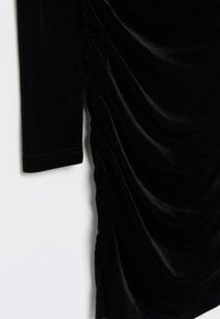 Robe en velours noir à manches longues, dotée de détails froncés sur le côté et d'une texture lisse et douce.