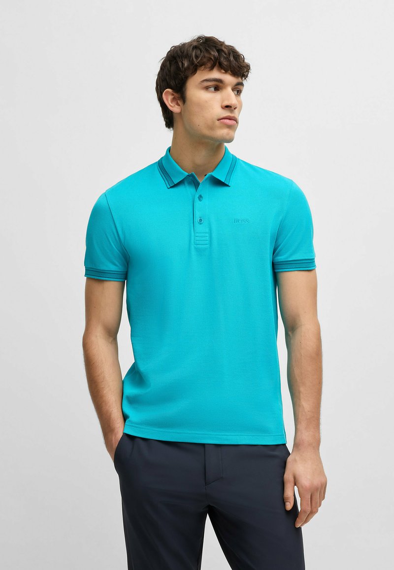 Turkos polo skjorta med klassisk krage, korta ärmar och subtil broderad logotyp. Slinky tyg med en figurnära silhuett.