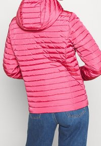 Vadderad rosa jacka med horisontell quiltad mönster, huva och långa ärmar. Materialet verkar slätt och glänsande. Lättviktsdesign.