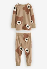 Pajama set u boji tamne bež koja se sastoji od dugih rukava i usklađenih hlača. Obe komade krasi ponavljajući uzorak lica medveda u smešnim smešnim tonovima smeđe boje.