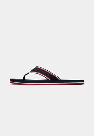 Meri flip-flop tummansininen, kumipohjalla, tekstiiliripätareilla, joissa on punaisia ja valkoisia raitoja, sekä "HILFIGER"-logo. Minimalistinen muotoilu ja kevytrakenteisuus.
