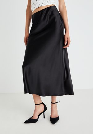 Black satin midi skirt with a smooth texture, flowing shape, and a high waist, paired with black pointed toe heels.