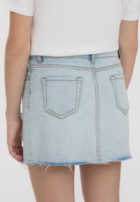 Gonna di jeans di un blu chiaro con orlo sfilacciato, due tasche posteriori, passanti per la cintura e un design aderente, che mette in risalto una texture liscia.