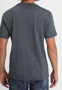 Camiseta de manga corta gris oscuro hecha de una tela suave, con un cuello redondo y un corte regular, que presenta una textura lisa y un diseño minimalista.