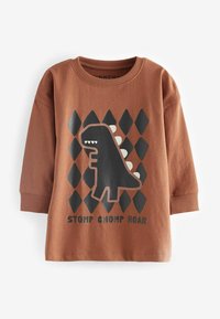 Brązowa koszula z długim rękawem z czarnym grafiką dinozaura z białymi akcentami i wzorem w romby poniżej, nadrukowany tekst brzmi "STOMP CHOMP ROAR."