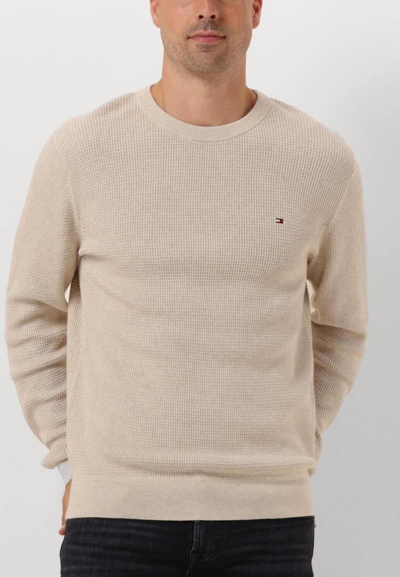 Maglione lavorato a maglia beige con un motivo strutturato, scollatura a girocollo, polsini e orlo a costine. Presenta un piccolo logo ricamato sul lato sinistro del petto.
