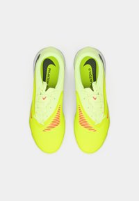 Para neonowozielonych butów sportowych Nike Phantom z różowymi akcentami i czarnymi logo Swoosh, widziana z góry na białym tle.