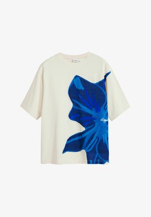 Camiseta de algodón blanca con un gran estampado floral azul en la parte frontal. Manga corta y un diseño de corte relajado.