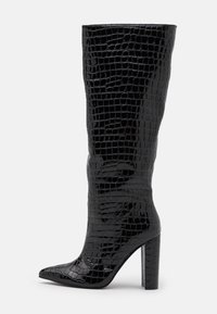 Bottes noires montantes jusqu'aux genoux avec une finition brillante à texture crocodile. Bout pointu et talon haut et épais. Silhouette ajustée et élégante.