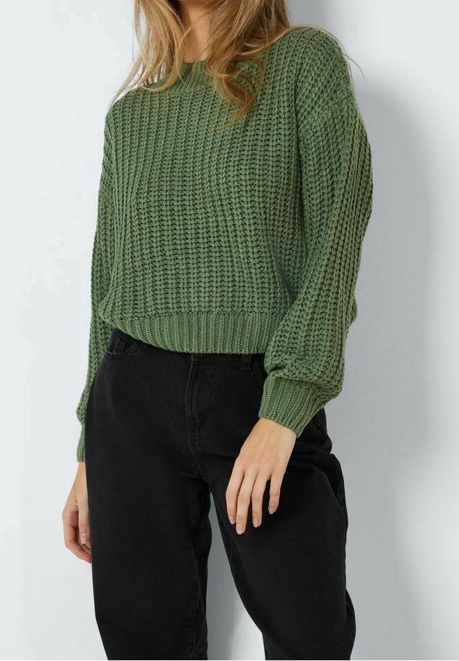 Grüner gestrickter Pullover mit strukturierter Musterung, rundem Ausschnitt und gerippten Bündchen. Kombiniert mit schwarzen Hosen in entspannter Passform.