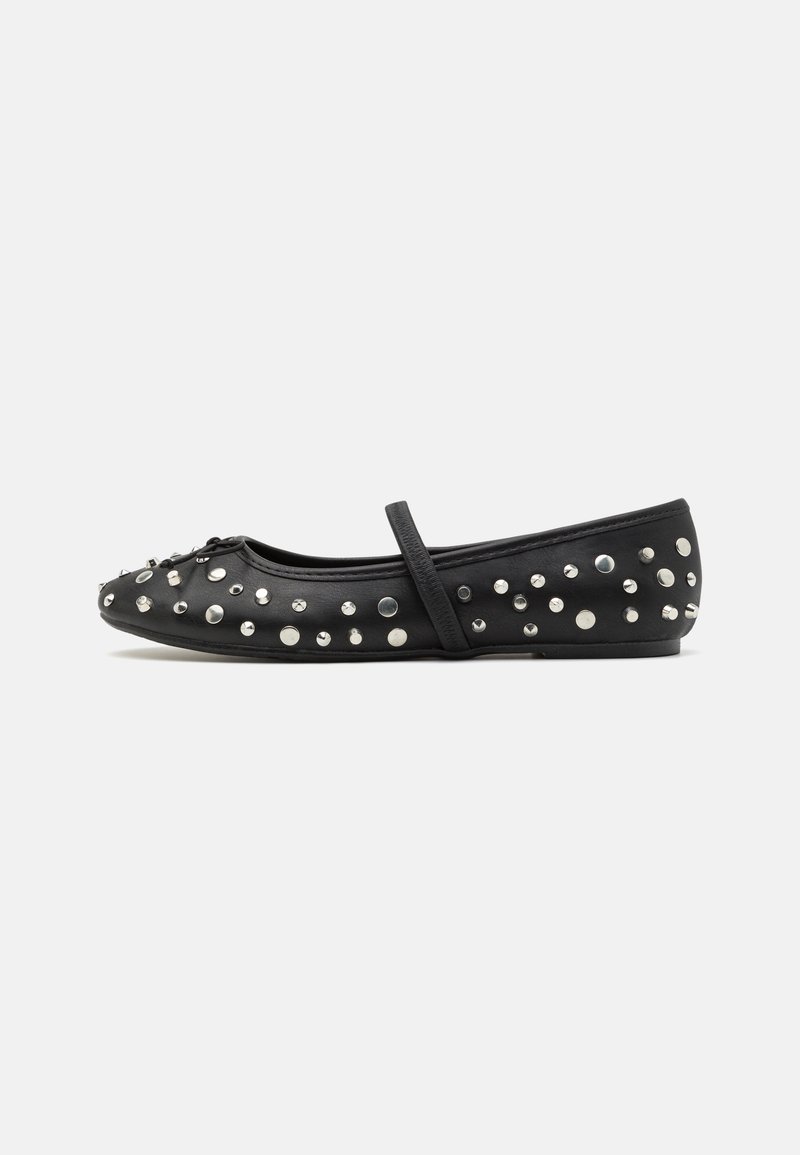 Chaussure plate noire Mary Jane avec des clous argentés et une seule bride sur le coup de pied, vue de profil sur fond blanc.