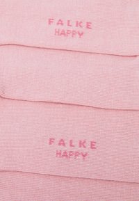 Divas viegli rozā krāsas zeķu pāri, salocīti, ar uzrakstu "FALKE HAPPY" tumšākā rozā krāsā uz zolēm.