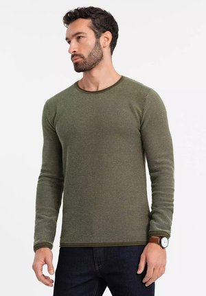 Groene lange mouwen shirt van textuurstof, met een ronde hals en contrasterende afwerking. Draagt bij donkere jeans en een horloge.