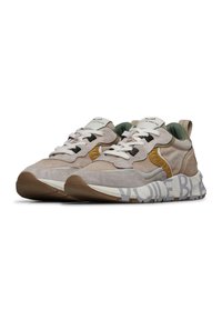 Sneaker in suede beige con dettagli in rete, suole in gomma marrone, lacci neri e un collare imbottito verde. Presenta un testo audace sulla suola.
