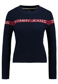 Maglione in maglia blu navy con maniche lunghe e una striscia orizzontale rossa sul petto e sulle braccia, con testo bianco "Tommy Jeans".