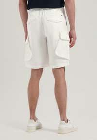 Weiße Leinen-Cargo-Shorts mit mehreren Seitentaschen, einer lockeren Passform und einem Saum, der knapp über dem Knie endet. Mit einem Knopfverschluss.