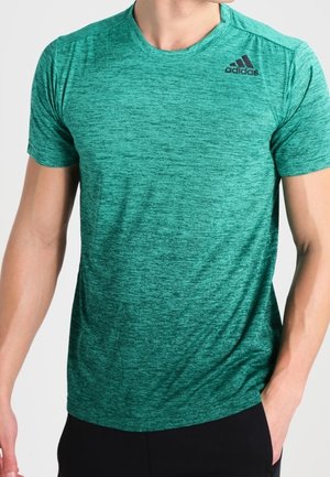 Mann trägt ein grün meliertes Adidas kurzärmeliges Sport-T-Shirt mit schwarzem Logo auf der oberen linken Brust.