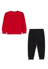 Rode sweatshirt met lange mouwen en een knoopdetail op de rug, gecombineerd met joggerbroek met zwarte elastische tailleband, beide gemaakt van zachte, comfortabele stof.