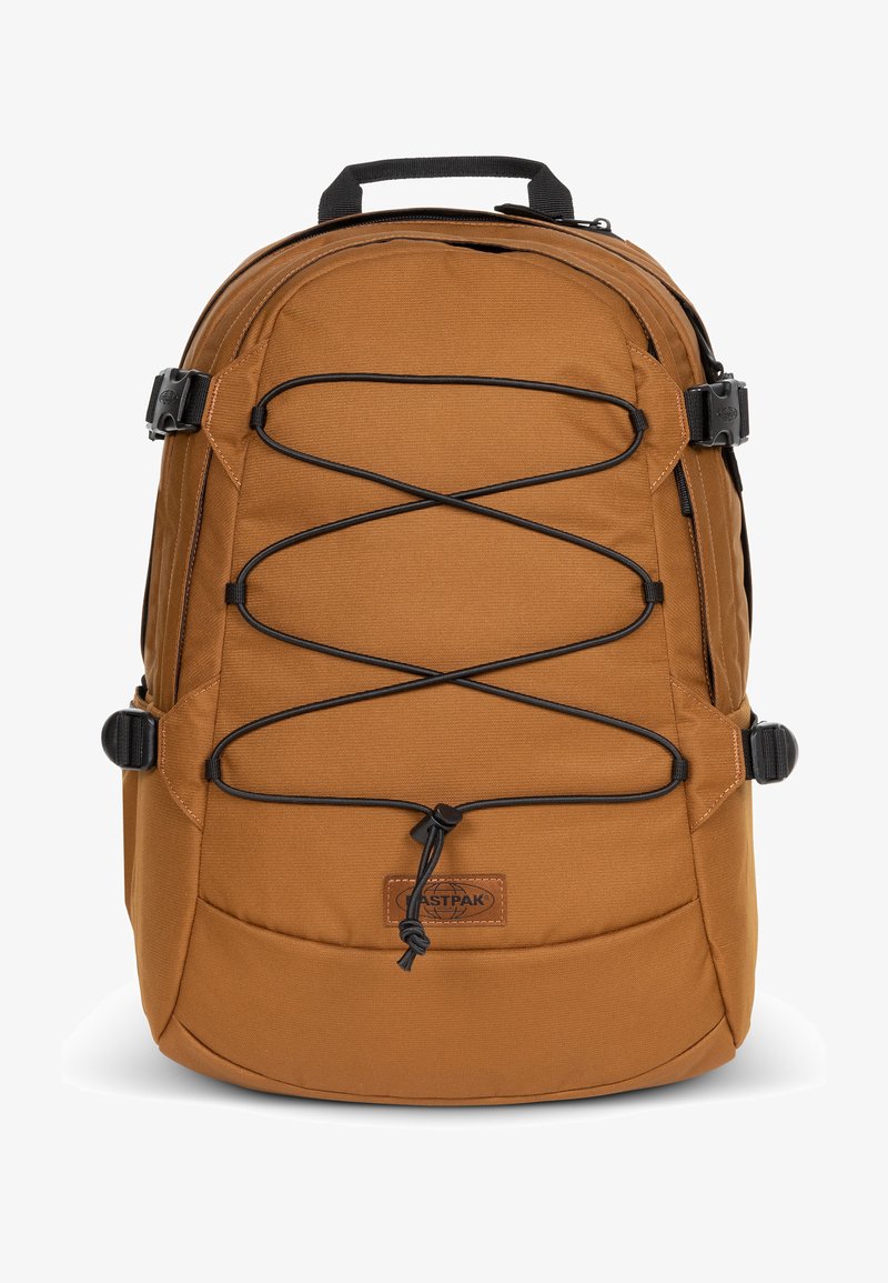 Ruskea kangaskassi, jossa on teksturoitu pinta, etuosassa bungee-nauhasuunnittelu, säädettävät sivuhihnat ja ylhäällä kantokahva. Sisältää logopatchin.