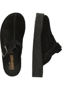Svarta mocka-kloggs med rund tå, justerbart rem med silverfäste och texturerad sula. Inuti finns varumärkeslogotyp i guld.