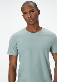 Lyseblå kortærmet t-shirt lavet af struktureret stof med rund halsudskæring, tætsiddende design og diskret ribbet detaljer.