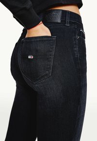 Svarta denimjeans med en figurnära passform, med en bakficka som har en liten logopatch och synliga sömnadsdetaljer. Läderetikett på midjebandet.