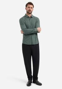 Groen gestreept shirt met een button-down kraag, lange mouwen en zwarte broek. Het shirt heeft een gestructureerd ruitpatroon.