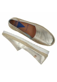 Metallische gouden espadrilles met een leren bovenwerk met textuur, contrasterende witte rubberen zool en beige stiksels langs de rand.