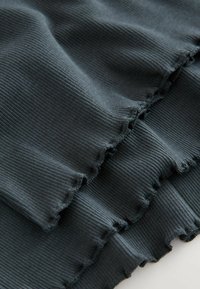 Dark green ribbed fabric with a textured surface, featuring ruffled edges and a soft, flowing design. Ideal for skirts or garment trims.