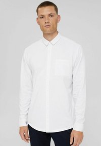 White long-sleeve shirt with a button-down collar and a single chest pocket. Smooth fabric with a classic fit, featuring a curved bottom hem.
