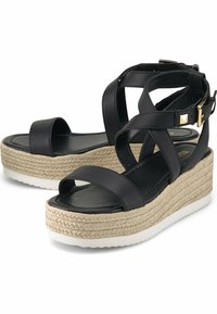 Czarne skórzane sandały na platformie z krzyżującymi się paskami wokół kostki, złotą klamrą, plecioną jutową wkładką i białą gumową podeszwą.