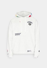 Sweat à capuche blanc avec poche kangourou à l'avant, accents multicolores sur la capuche, texte et logos noirs imprimés incluant "AAPEUNVS" et "Somewhere in the Aape Universe."