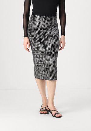 Jupe crayon noire et blanche à motifs géométriques, de longueur genoux, accompagnée de talons noirs à lanières. Tissu doux et extensible.